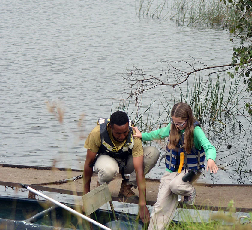 A Masatu guide walking with a young child at Lake Duluti, showing family-friendly guiding